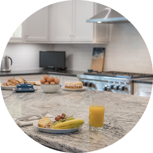 Granite countertop island with stainless steel appliances, white cabinets, and breakfast setup by California HarborCrest Kitchen Design